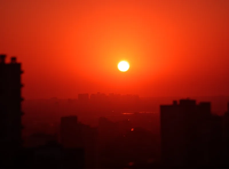 A dramatic sunset over a European city, tinted orange by Saharan dust.