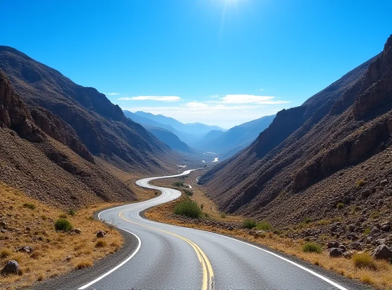 A winding road snaking through a dramatic mountain pass in Lesotho, with clear blue sky overhead.