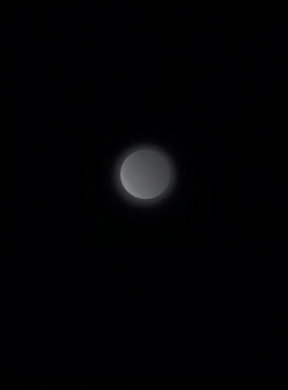 A partial solar eclipse seen through a telescope, with the sun partially obscured by the moon.