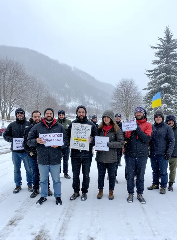 Protesters holding signs in front of a snowy mountain backdrop.