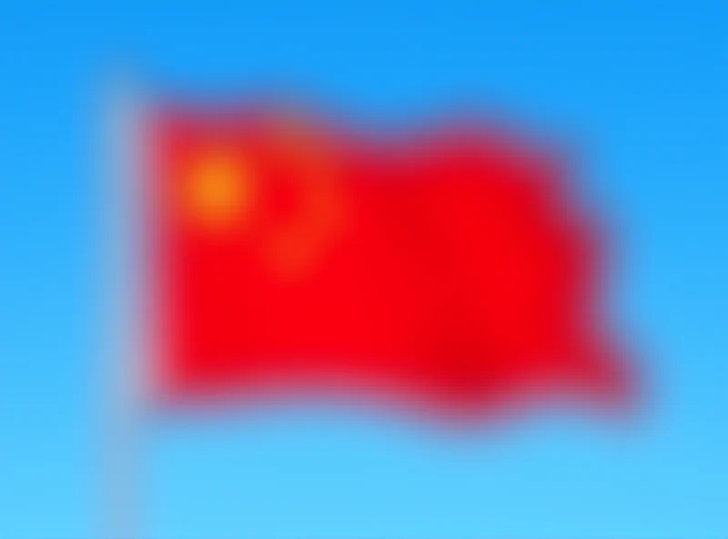 Chinese flag waving in the wind against a blue sky